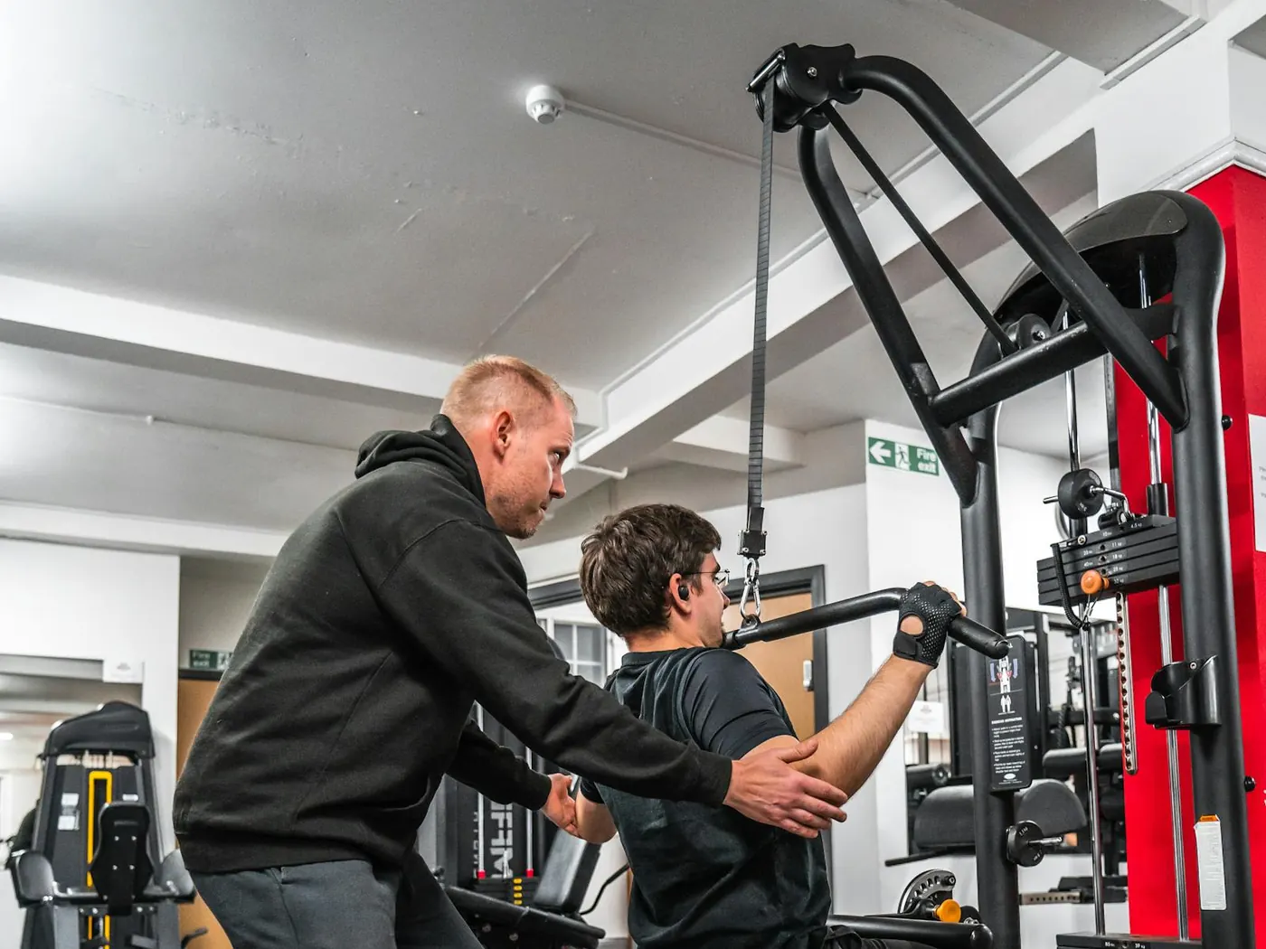 Coach guiding a client on a strength machine